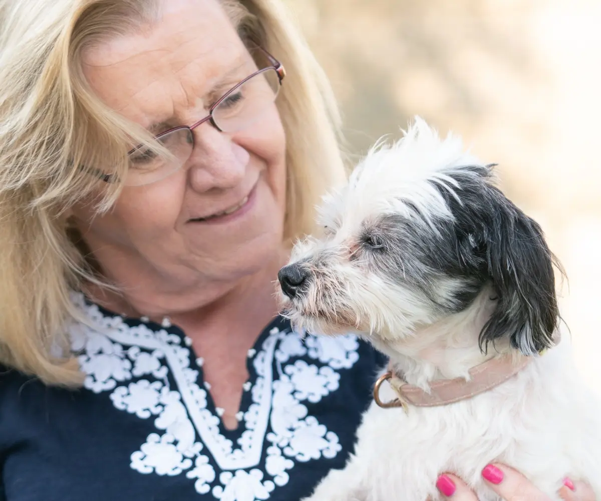 Woman holding and looking at her small black and white dog